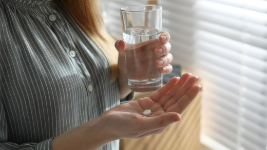 Woman holding a pill and a glass of water Woman holding a pill and a glass of water